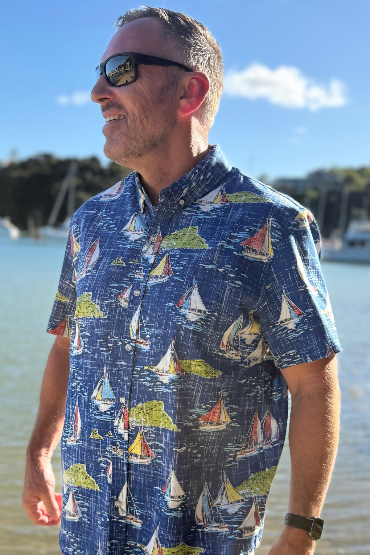 Man wearing a colorful shirt with sailboat pattern on a blue shirt