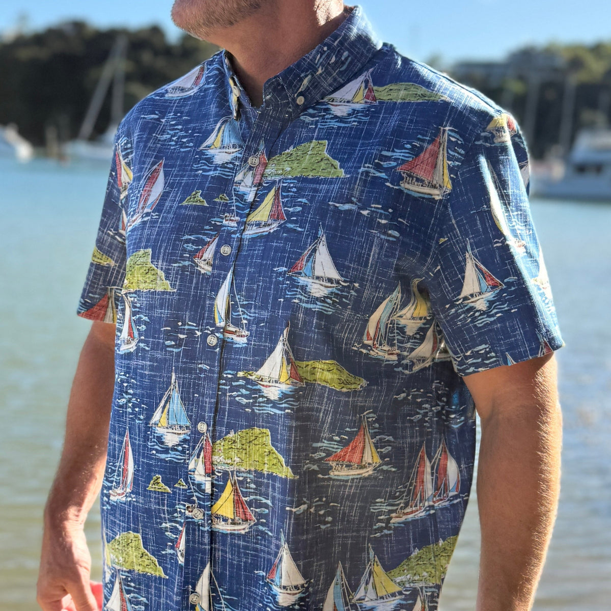 Man wearing a colorful shirt with sailboat pattern on a blue shirt
