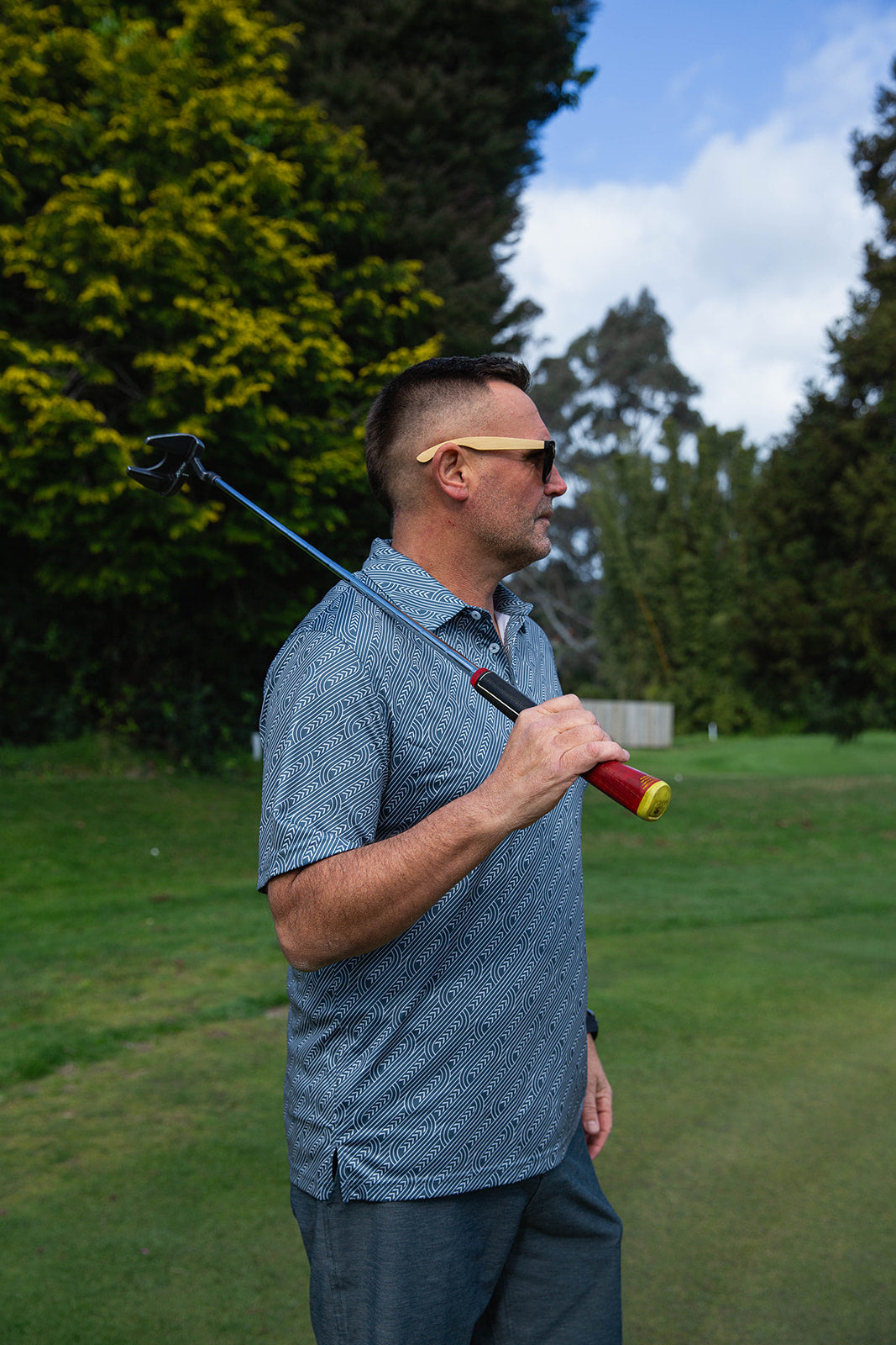 Pakati Men’s Golf Polo in dark grey with Māori-inspired geometric design. NZ golf shirt made from breathable, quick-dry performance fabric.