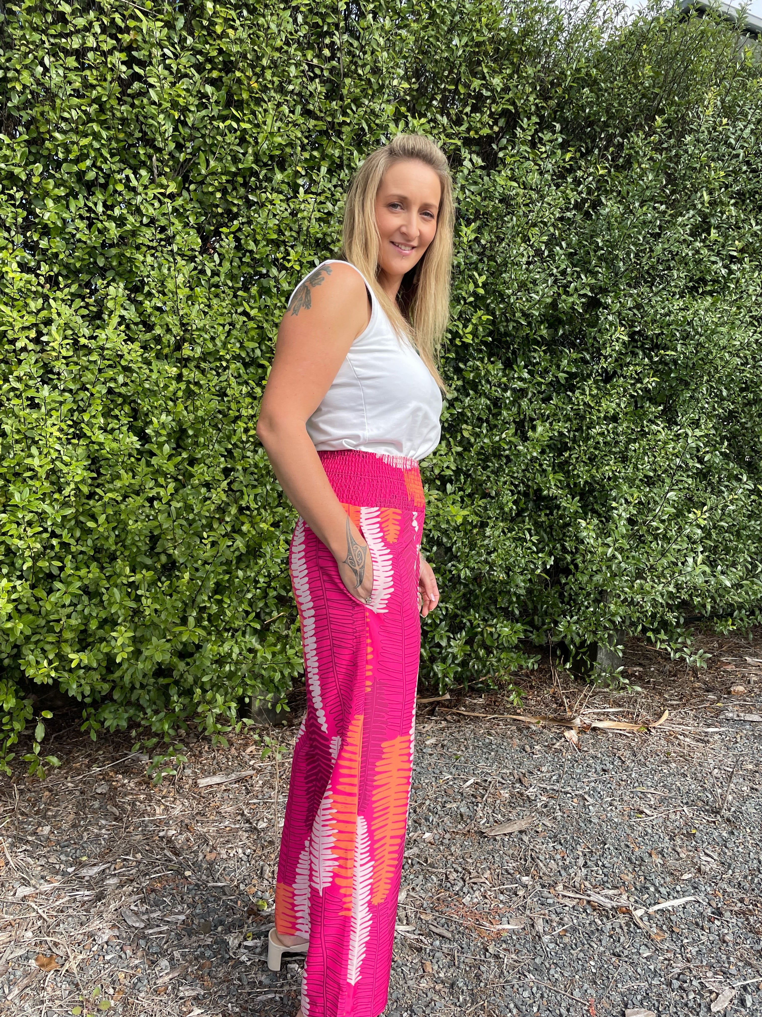 Women’s wide-leg pants in hot pink with Piupiu fern print – bold New Zealand inspired smocked waist trousers