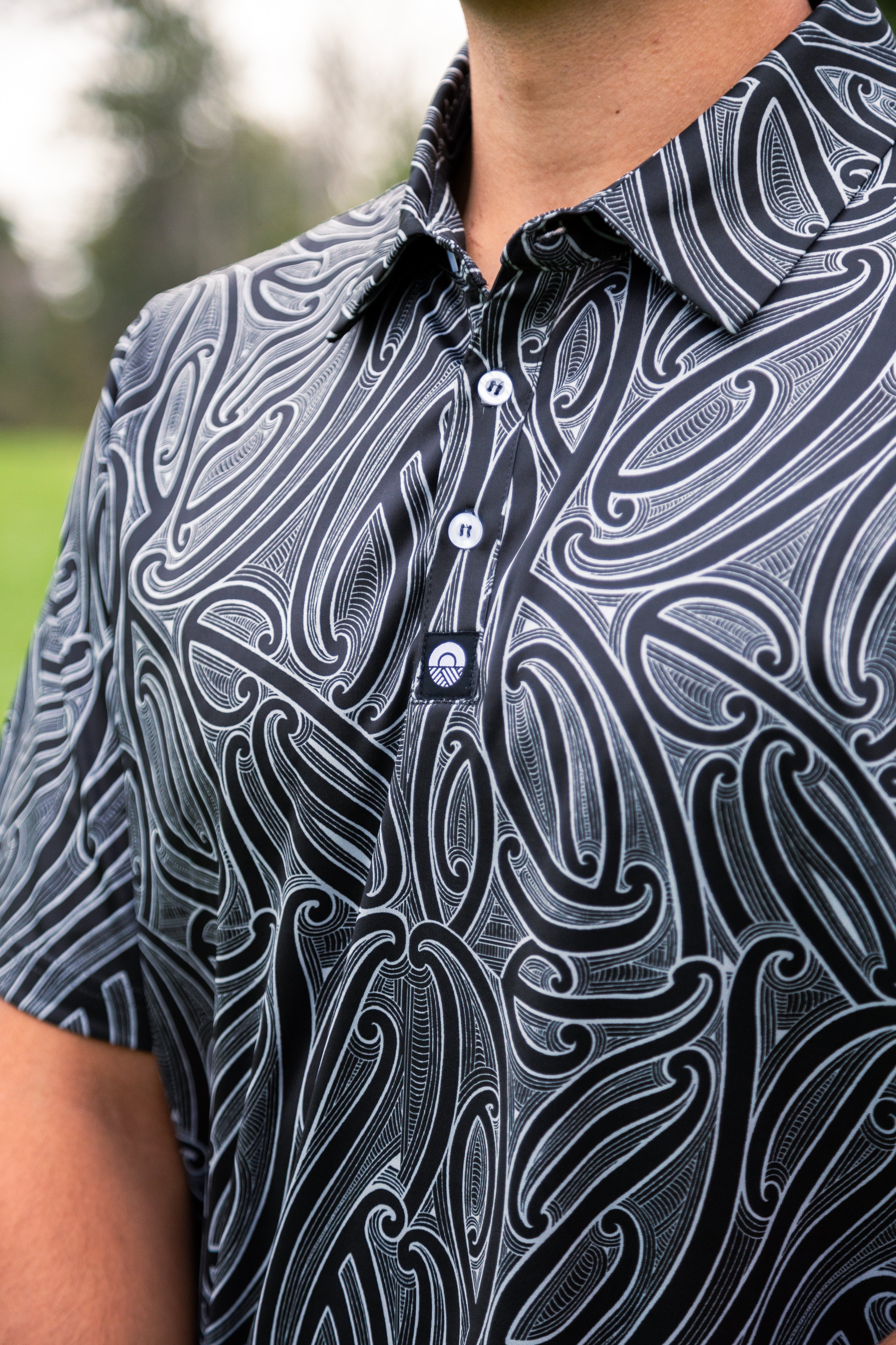 Men’s Kowhaiwhai golf polo shirt featuring bold black and white Māori-inspired design – premium performance golfwear from Kaleo New Zealand.