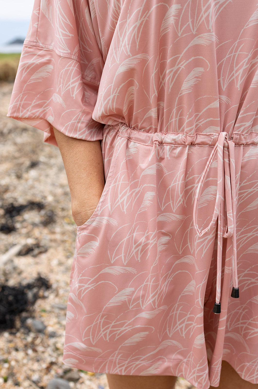 Women’s pink playsuit with white toe toe fern pattern – lightweight New Zealand inspired summer outfit with drawstring waist and short sleeves.