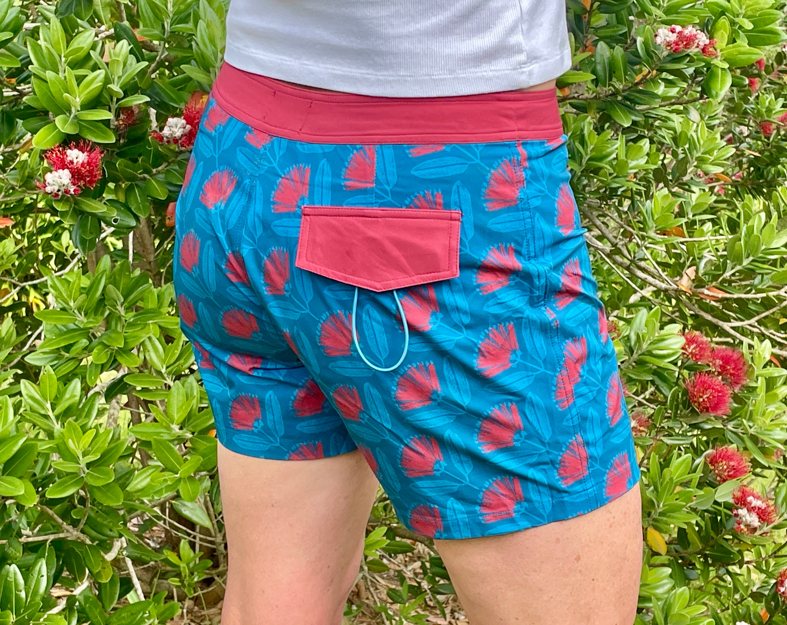 Women’s beachwear NZ – Pōhutukawa print board shorts, NZ-designed lightweight quick-dry boardies by Kaleo; travel-friendly holiday clothing with Kiwi style.