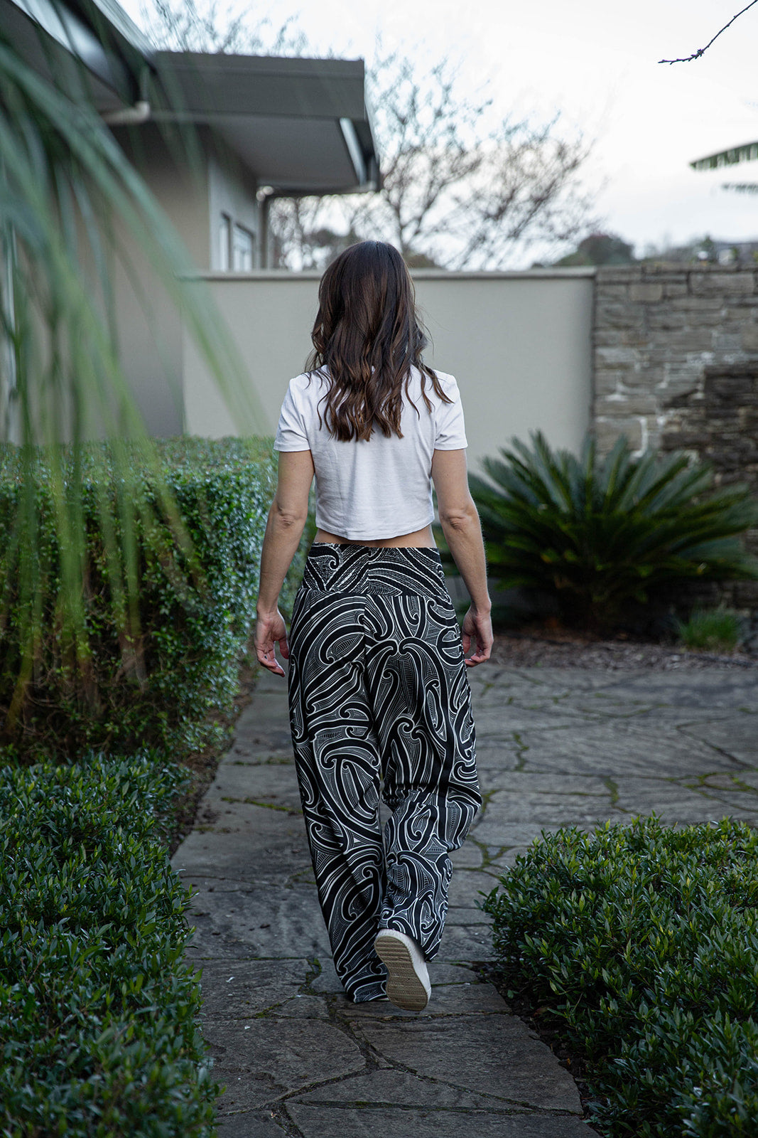 Woman wearing Kowhaiwhai smocked pants with Māori-inspired black and white kowhaiwhai pattern, stylish New Zealand women’s loungewear and casual streetwear pants