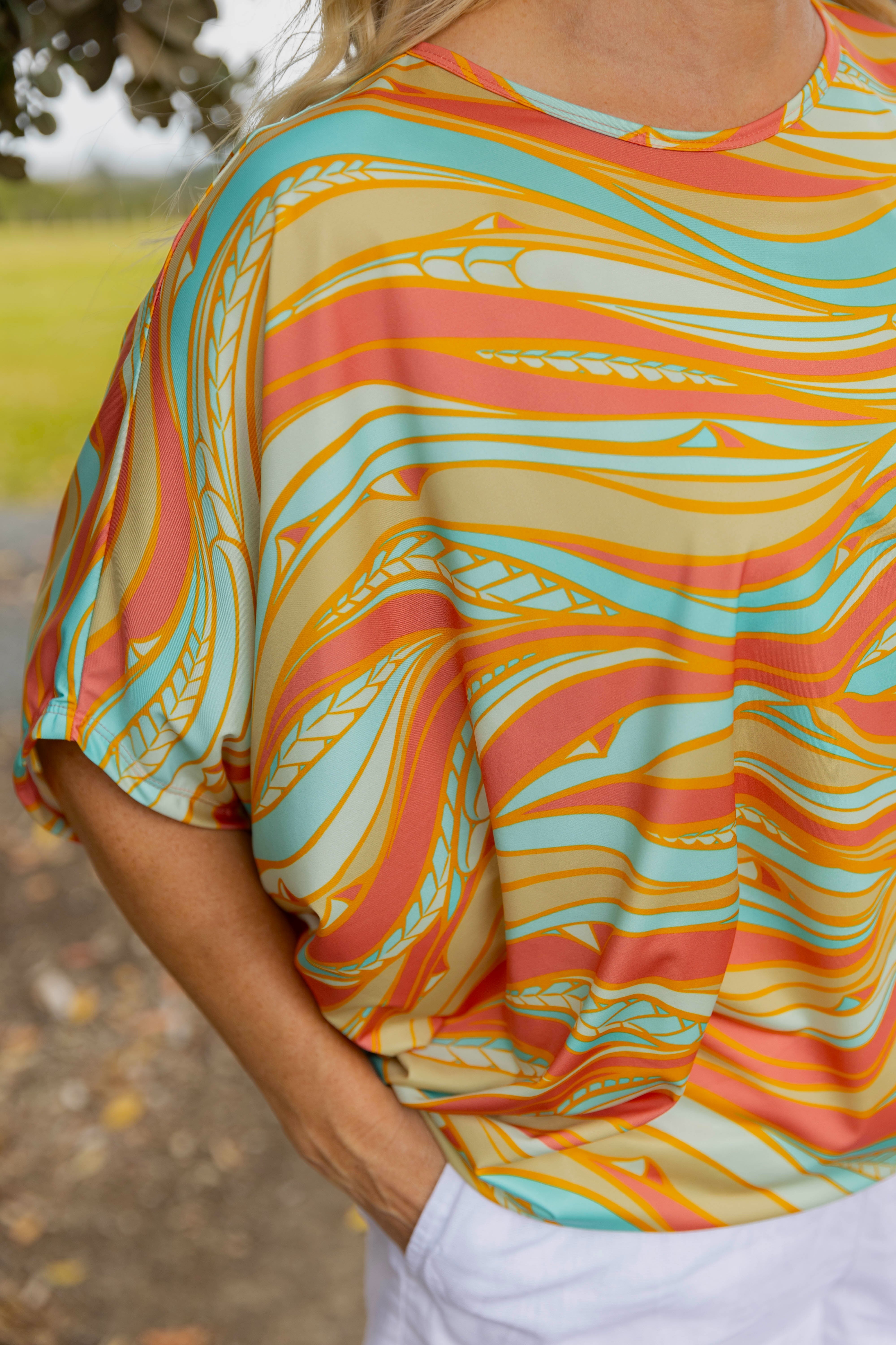 Women’s batwing top New Zealand – Te Rerenga coral print, NZ-designed wearable art by Kaleo; lightweight, travel-friendly women’s clothing with Kiwi style.