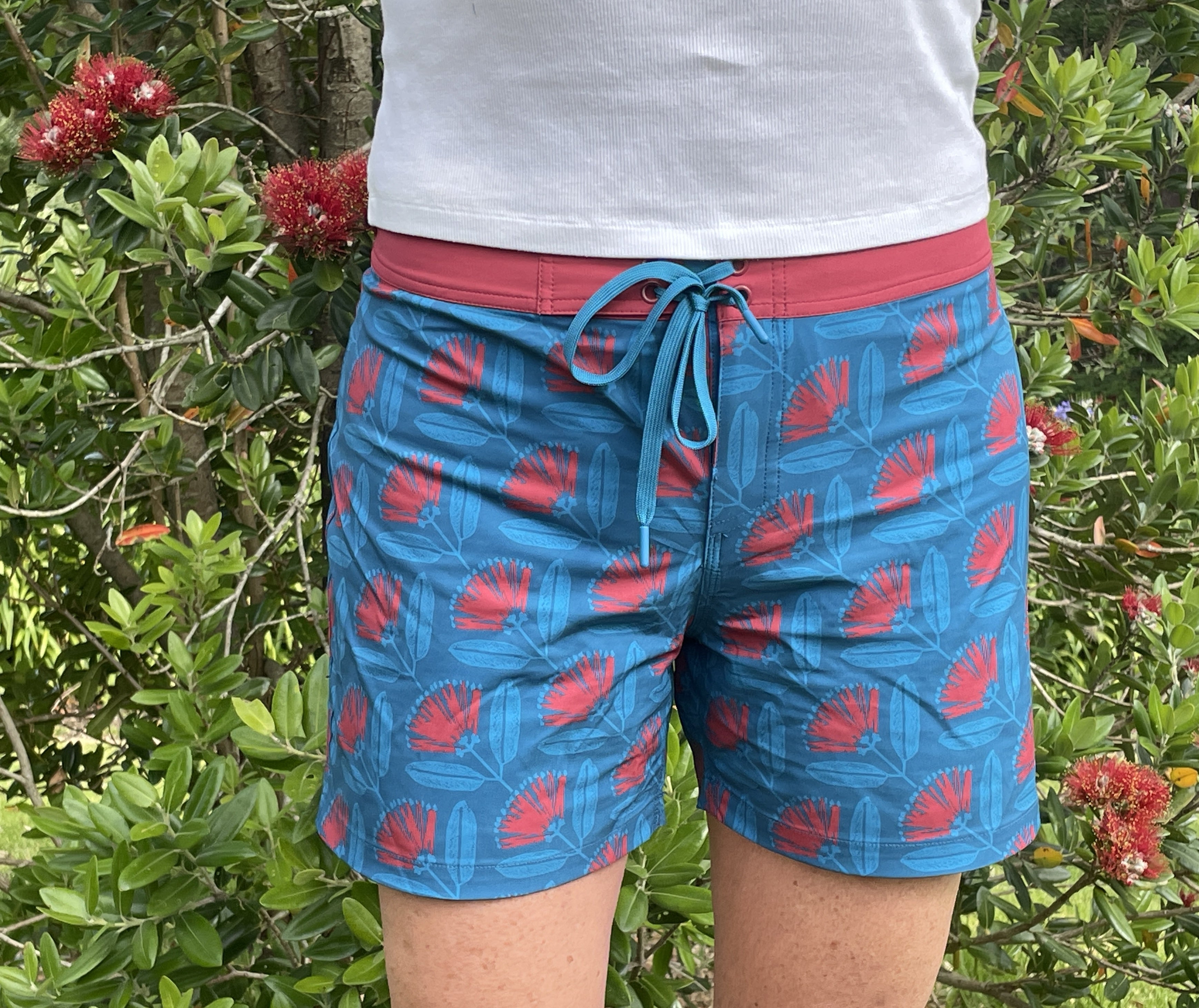 Women’s beachwear NZ – Pōhutukawa print board shorts, NZ-designed lightweight quick-dry boardies by Kaleo; travel-friendly holiday clothing with Kiwi style.