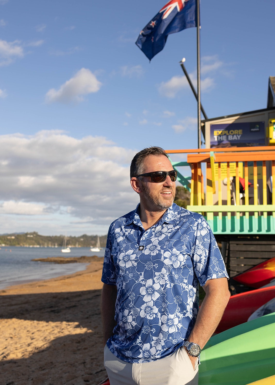 Men’s Puarangi New Zealand hibiscus golf polo in blue and white floral print. Designed with breathable, moisture-wicking performance fabric for comfort on and off the course. Perfect for summer golf, resort wear, and coastal living style.