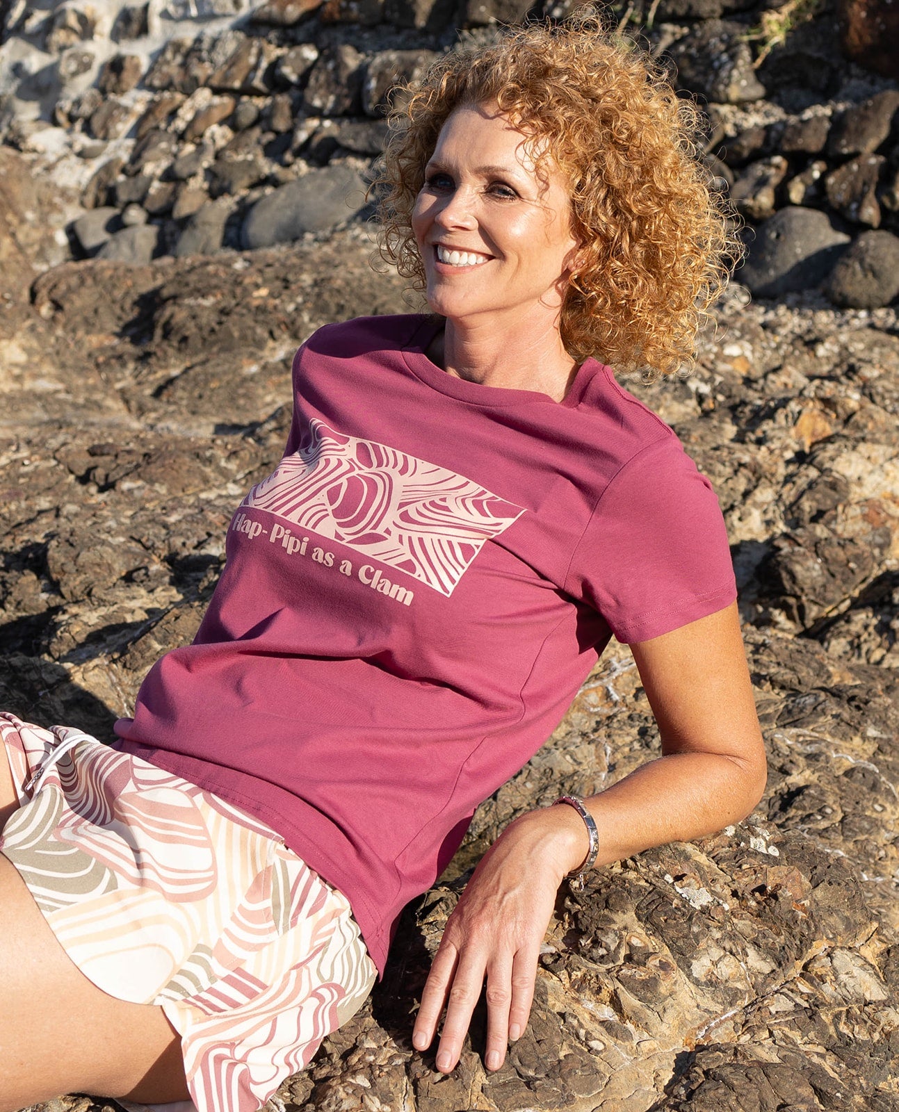 Women’s rose pink t-shirt with pipi shell print and fun slogan ‘Hap-Pipi as a Clam’ – playful New Zealand inspired graphic tee